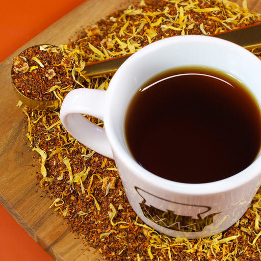 Cup of Peach Rooibos on top of mound of Peach Rooibos loose leaf tea.