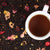 Cup of pomegranate cranberry tea surrounded by loose black tea and fruit
