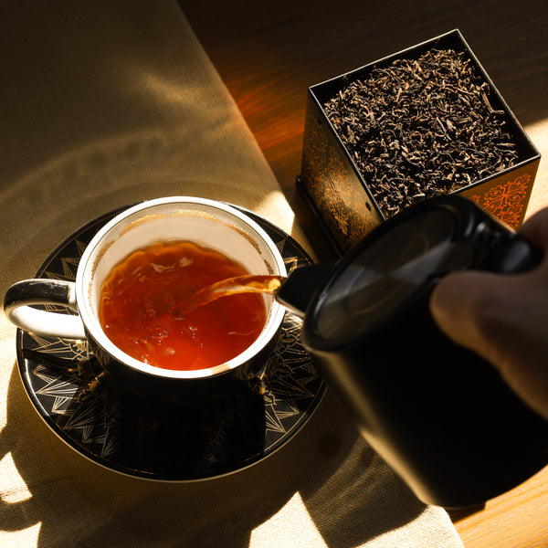 Brewed Pu-erh 3 Year Aged in Nordic Tea Pot being poured into Cup & Saucer set.