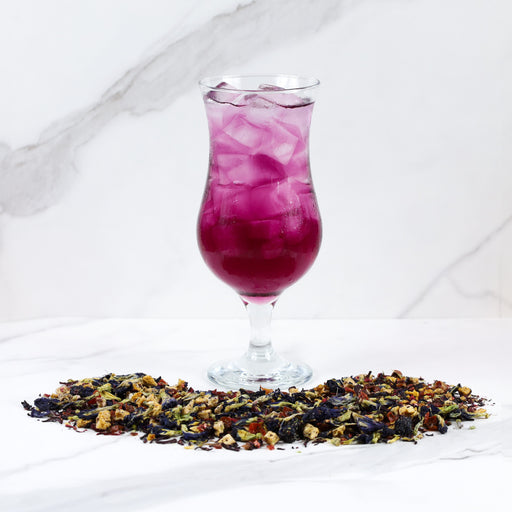 Glass of Purple Papayaberry next to Purple Papayaberry tea leaves.