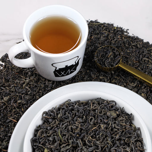Cup of brewed Purple Tea on top of loose leaf Purple Tea.