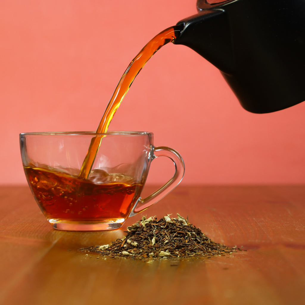 Pouring brewed Rooibos Chai tea into glass cup.