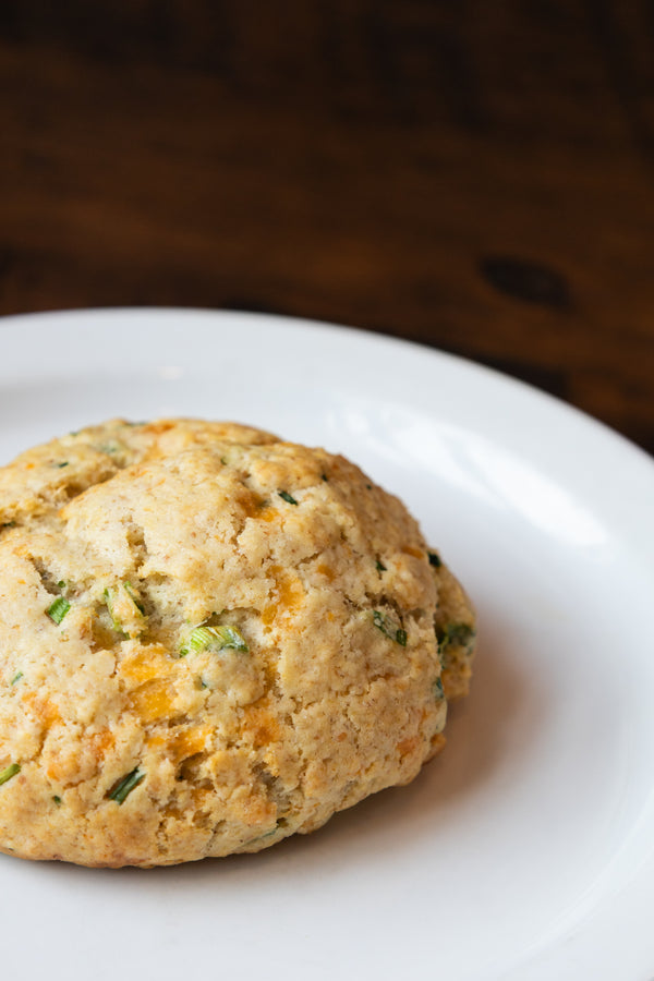 Savory Herb & Sour Cream scone with cheddar cheese, fresh herbs, and spices on a white plate
