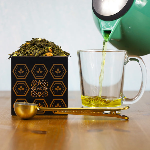 Glass of brewed Strawberry Orange next to Tea Tin filled with Strawberry Orange loose leaf tea.