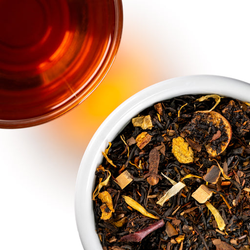 Overhead shoot of Taffy Apple loose next to a deep brown cup of tea on a white background. 