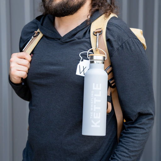 Person wearing The Whistling Kettle insulated tea flask clipped to a backpack strap with a built-in carry loop