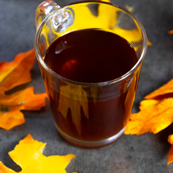 A cup of Vanilla Chai surrounded by autumn leaves.