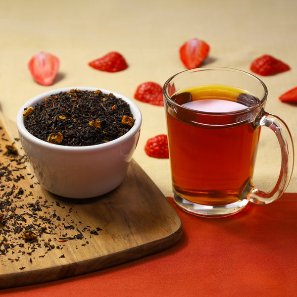 Vineyard Peach Strawberry tea in glass next to Vineyard Peach Strawberry tea leaves in bowl.