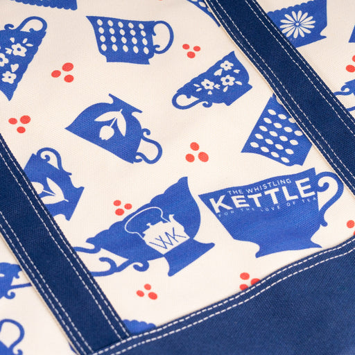 Detail of a cream and navy canvas tote bag featuring a blue teacup pattern and reinforced stitching