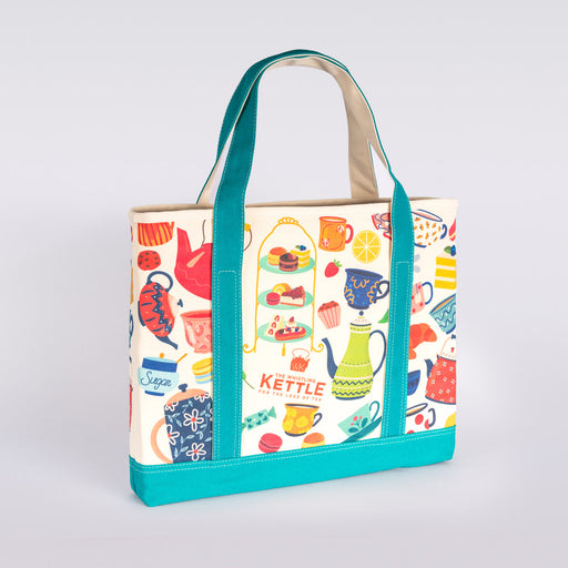 Cream and teal canvas tote bag featuring a colorful tea, teapot, and dessert pattern with reinforced handles