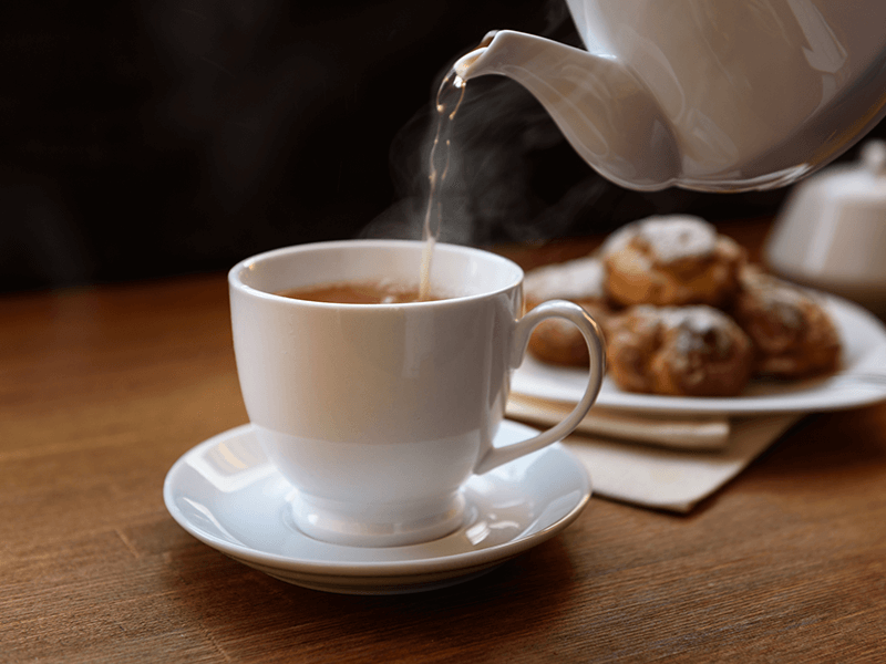 Tea is poured from a teapot into a mug