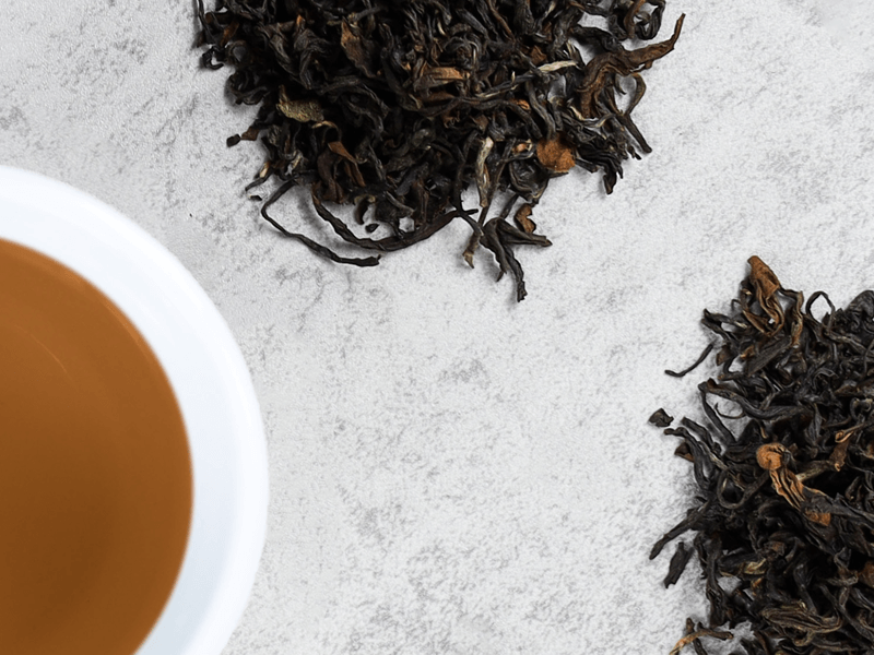 Piles of tea leaves surround a cup of brewed tea