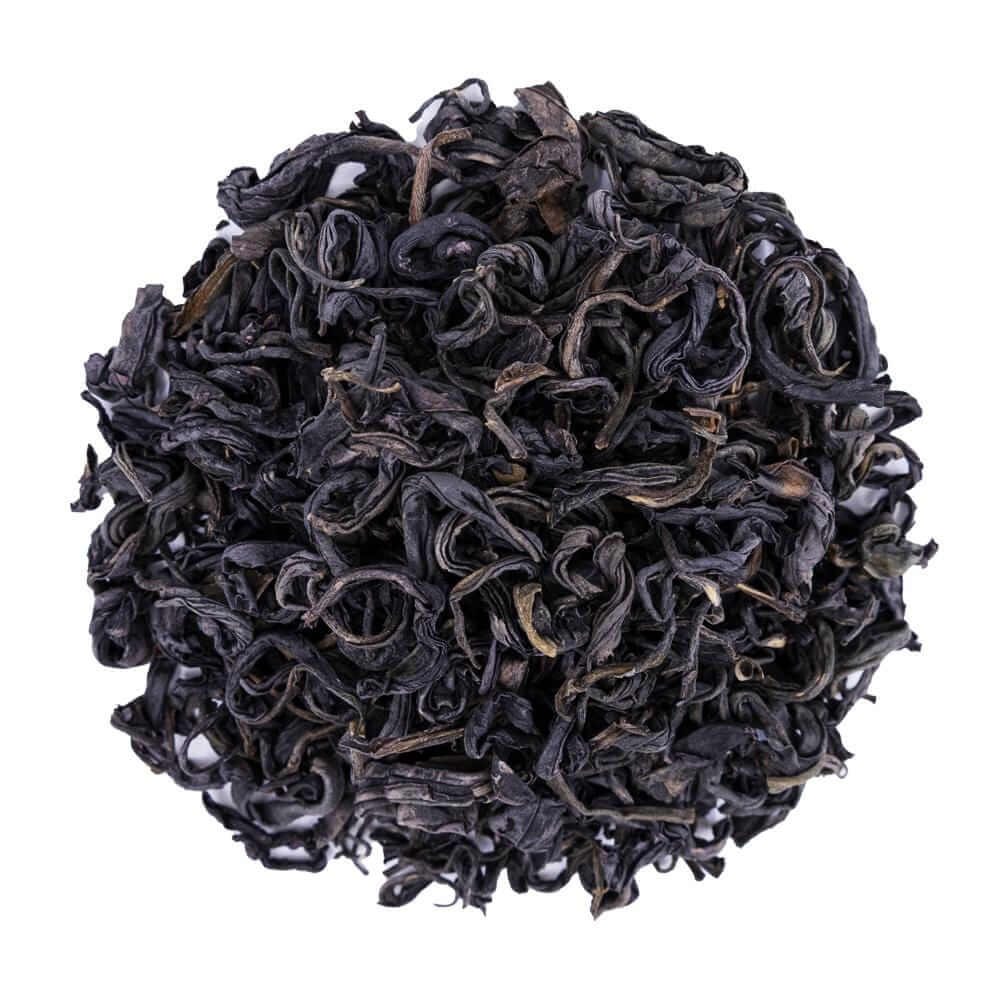 Top mound picture of The Whistling Kettle Purple Whole Leaf tea with curly dark leaves.